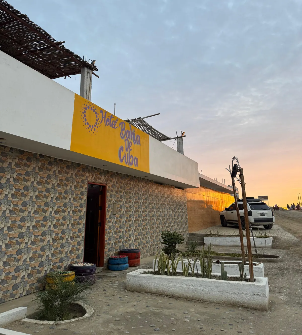Fachada del Hotel Bahía de Cuba al atardecer, con el letrero amarillo sobre la entrada